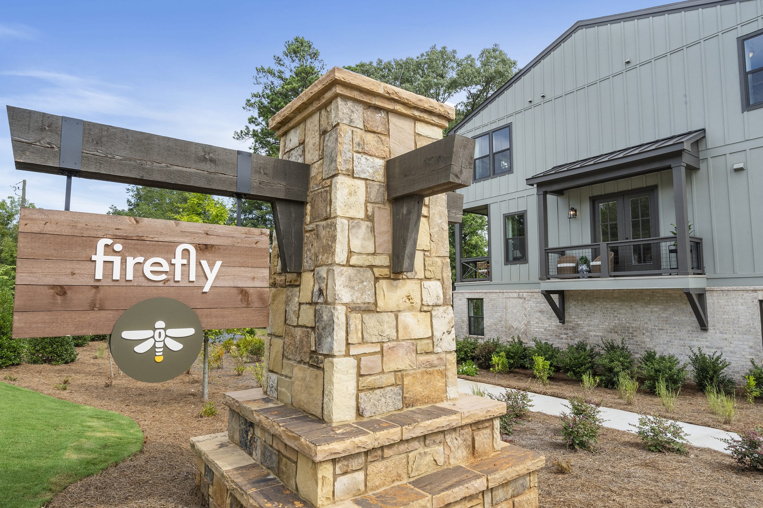 building with stone and wood sign 'firefly,' large windows, balcony, and landscaped greenery.