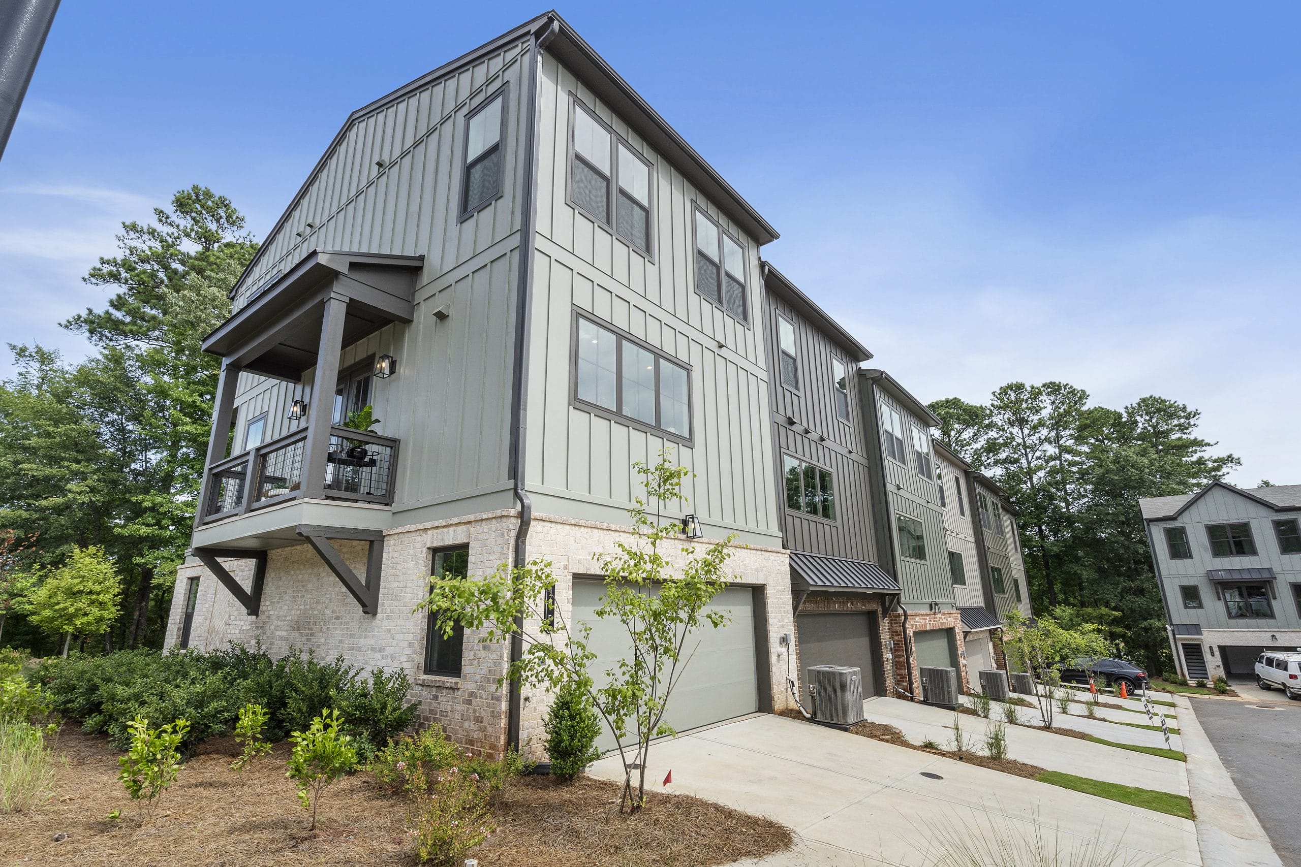Townhouses with large windows, balconies, landscaped front yards, and garages.