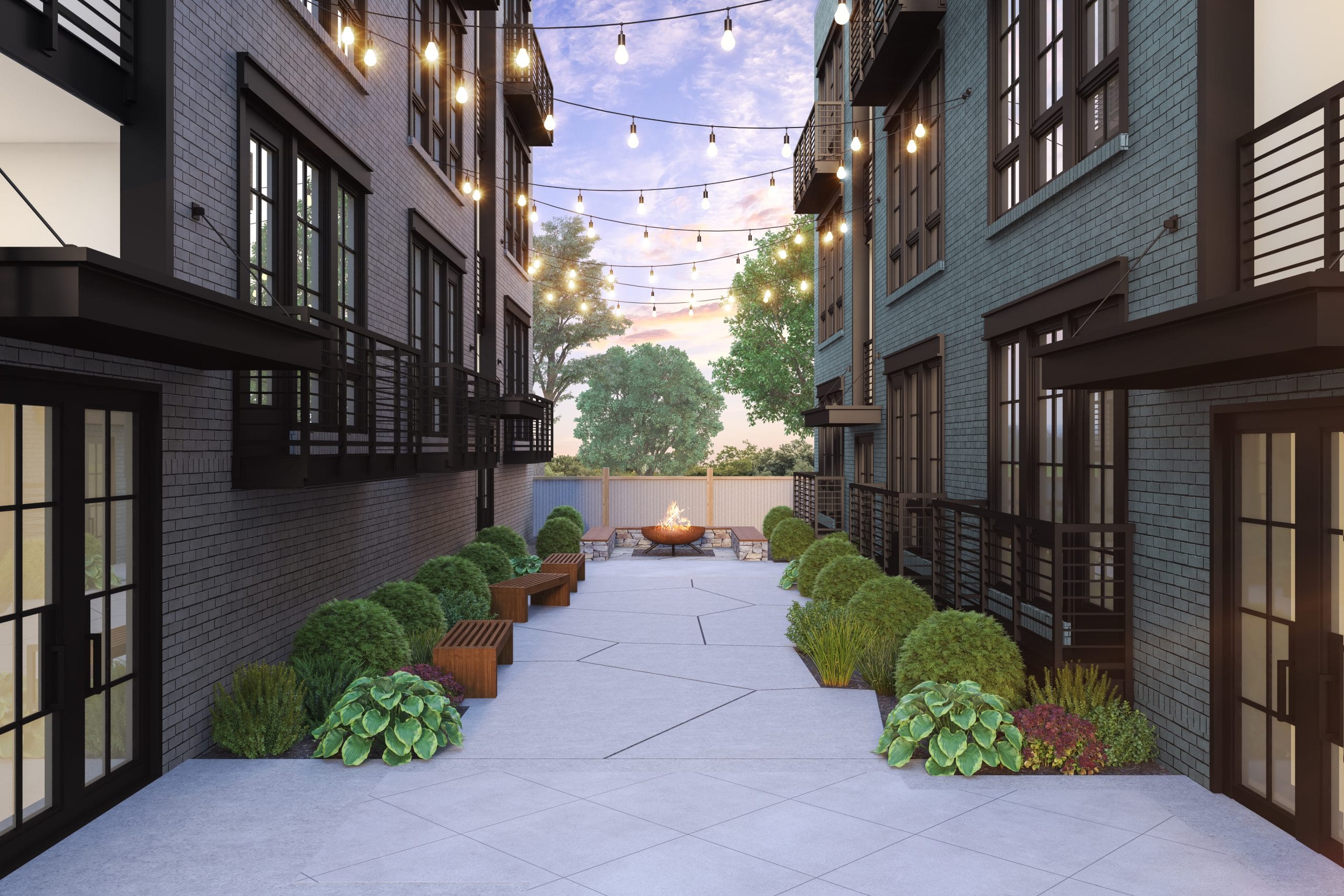 Outdoor courtyard between two buildings, decorated with string lights, plants and shrubs along the sides, benches for seating, fire pit surrounded by more seating, large windows and balconies overlooking the courtyard.