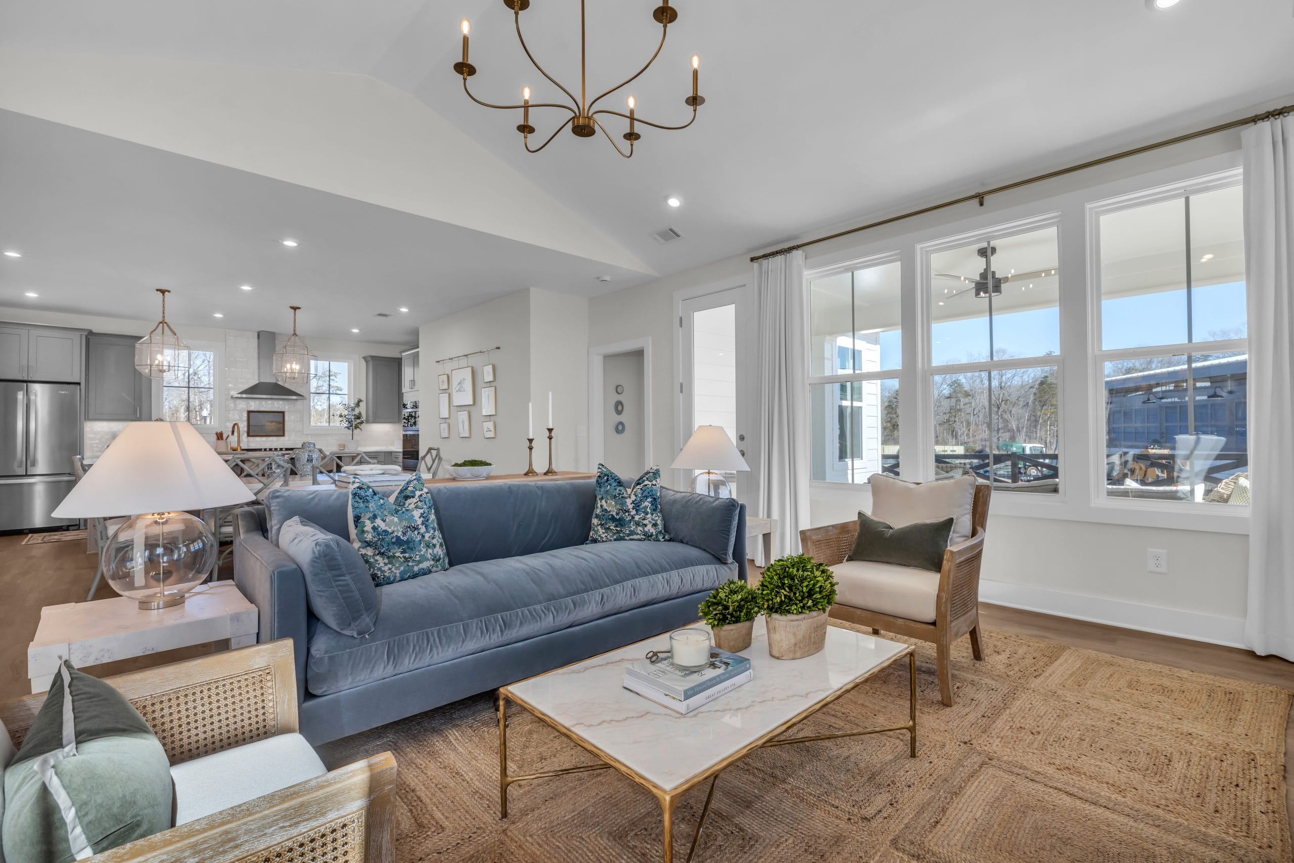Living room with blue sofa, patterned cushions, and open kitchen