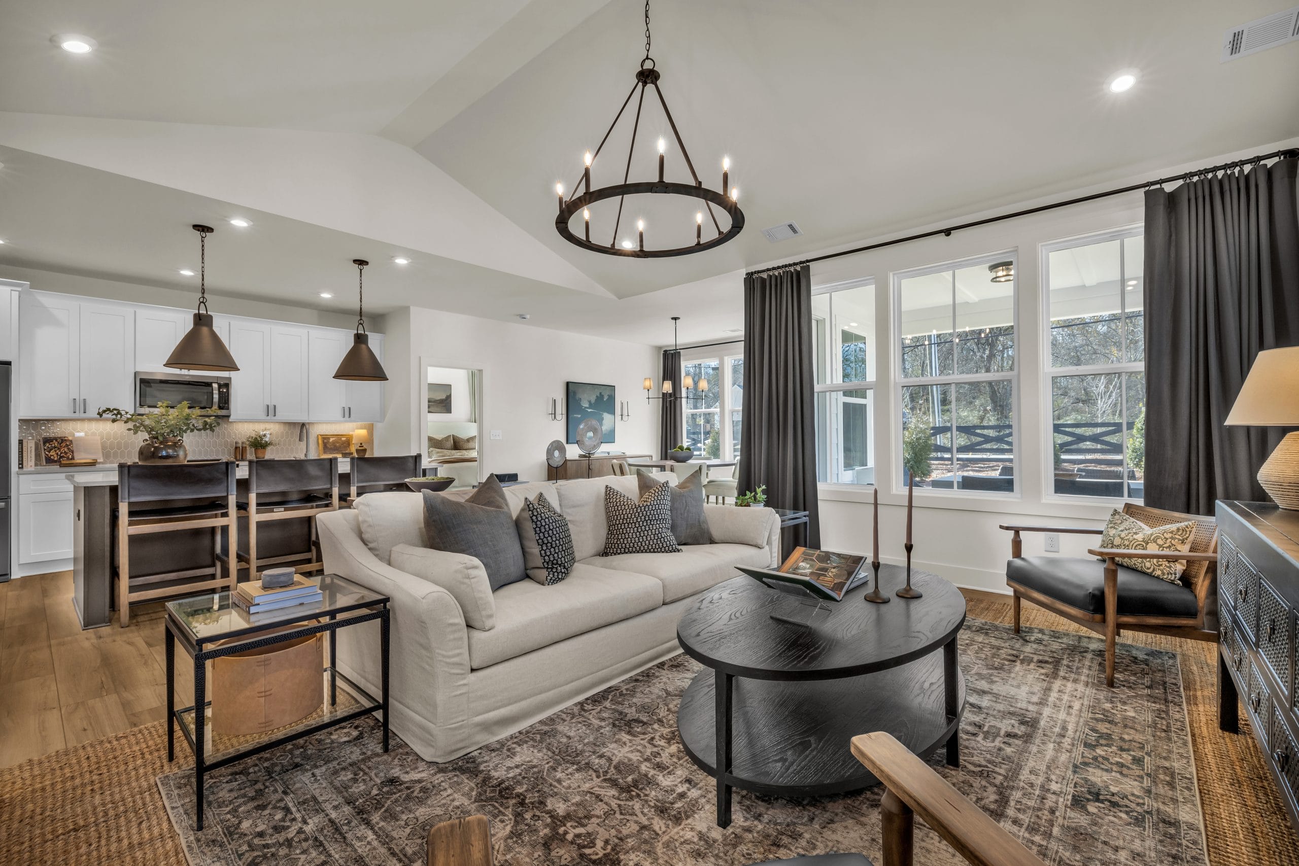 Living room with beige sofa, black coffee table, and kitchen island at sunset.