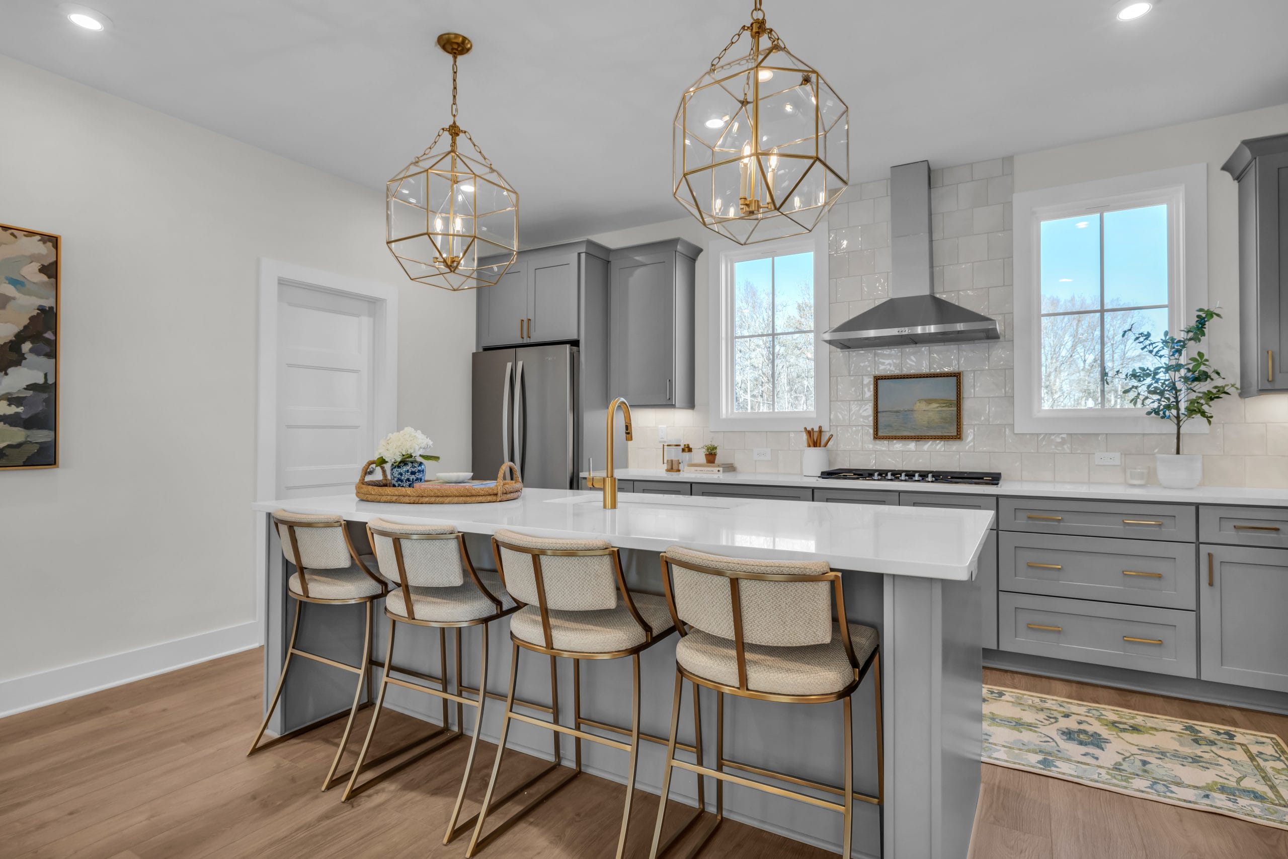 Kitchen with large island, gray cabinets, and pendant lights.