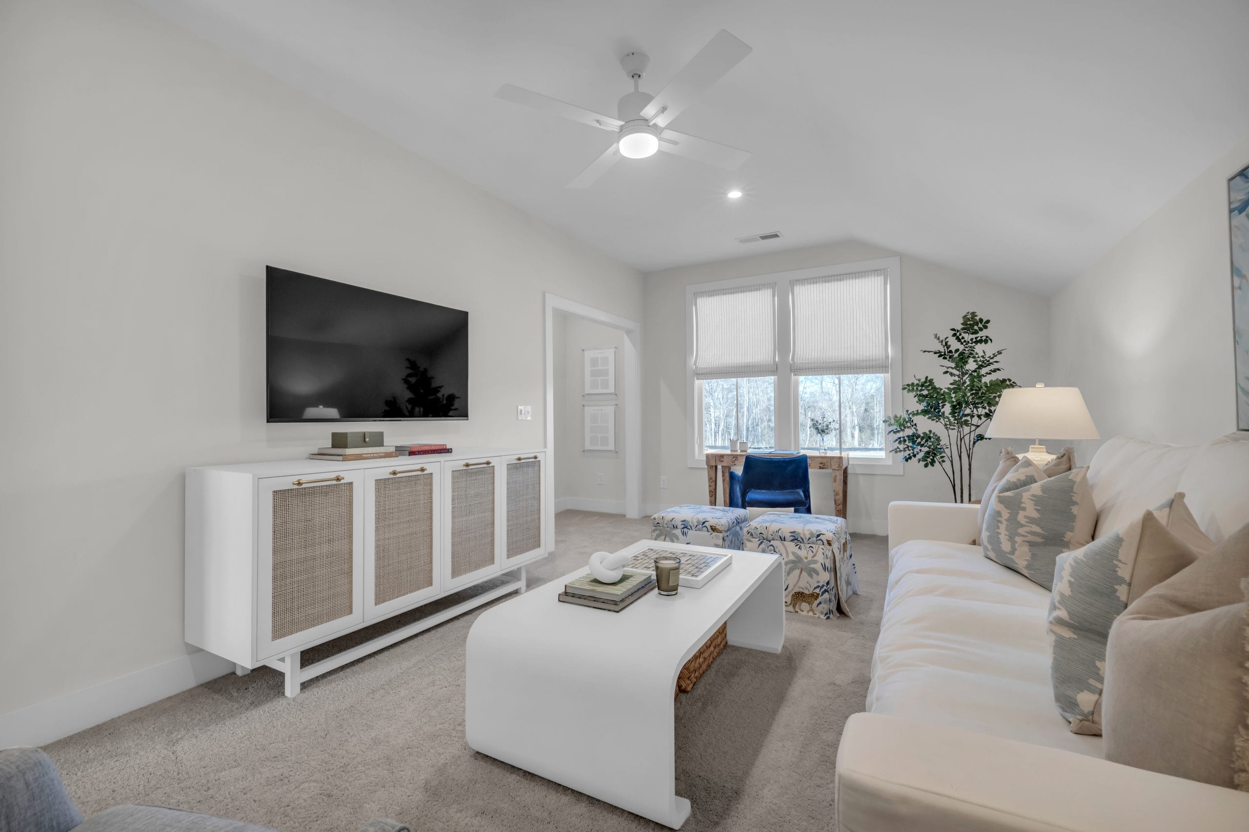 Modern living room with beige sofa, flat-screen TV, and white ceiling fan.