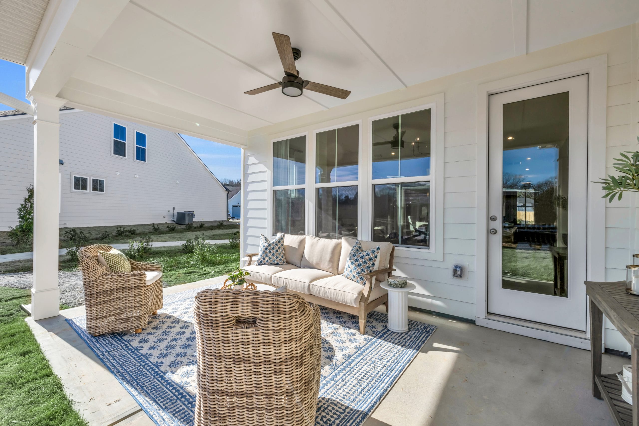 Outdoor patio with wicker furniture, ceiling fan, and patterned rug.