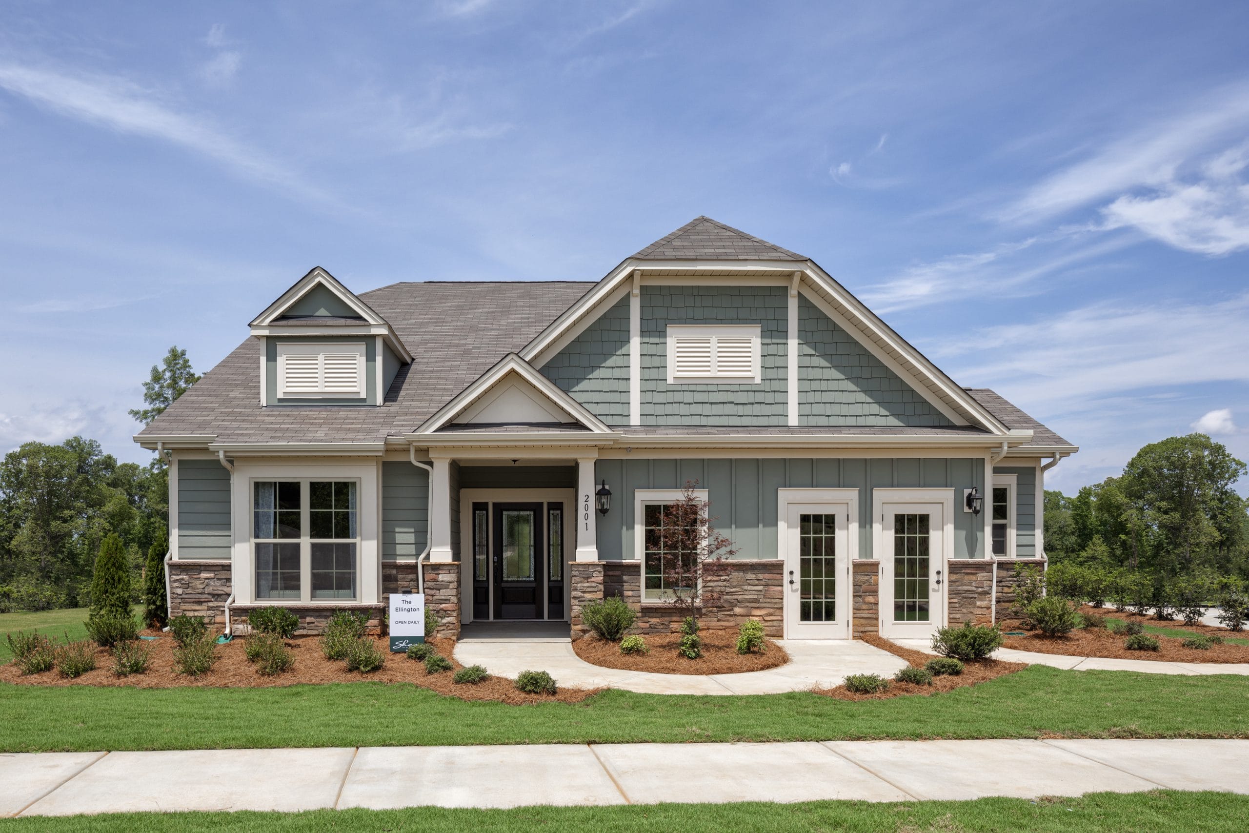 Single-story Ellington house by Empire Homes, featuring stone and siding exterior, gable roof, multiple windows, double front doors, well-maintained lawn, and landscaping.